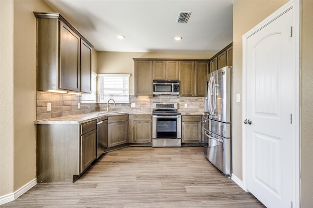 kitchen with stainless steel appliances, light countertops, visible vents, light wood-style flooring, and a sink