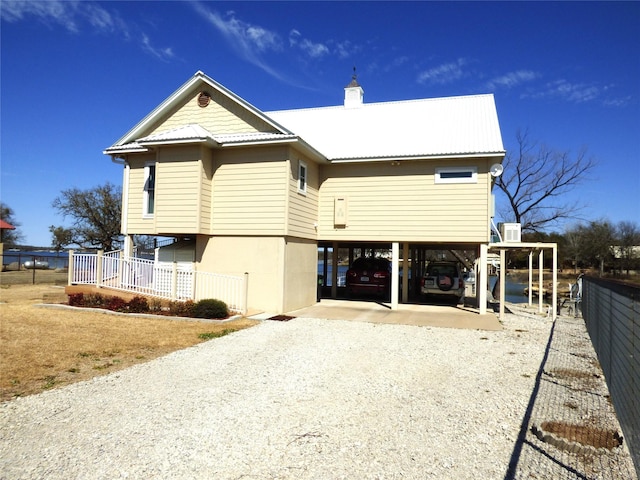 view of front of home with metal roof, a carport, fence, and driveway