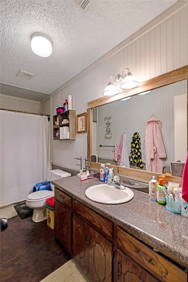 bathroom with curtained shower, toilet, vanity, a textured ceiling, and wood finished floors