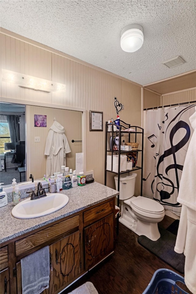 bathroom featuring curtained shower, toilet, a textured ceiling, vanity, and wood finished floors