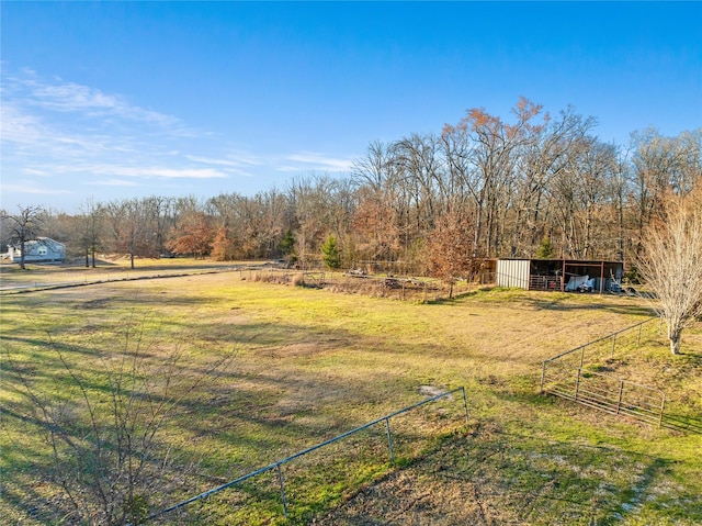 view of yard with an outbuilding, a rural view, an outdoor structure, and fence