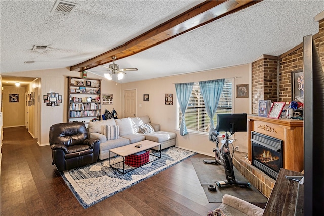 living room with a glass covered fireplace, visible vents, vaulted ceiling with beams, and wood finished floors