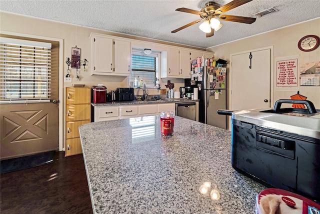 kitchen featuring stainless steel appliances, visible vents, dark wood-type flooring, white cabinetry, and a textured ceiling