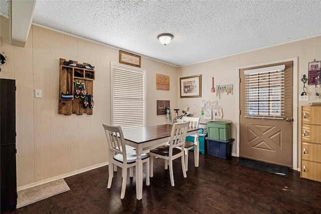 dining area featuring a textured ceiling, baseboards, and wood finished floors