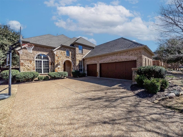 french provincial home featuring a garage, brick siding, concrete driveway, stone siding, and roof with shingles