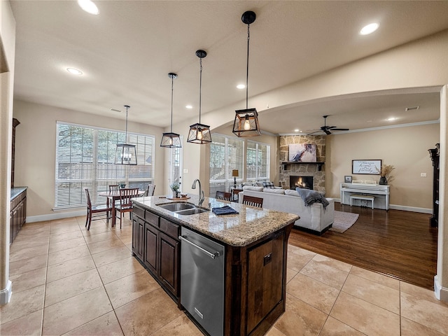 kitchen featuring a fireplace, stainless steel dishwasher, a ceiling fan, light tile patterned flooring, and a sink