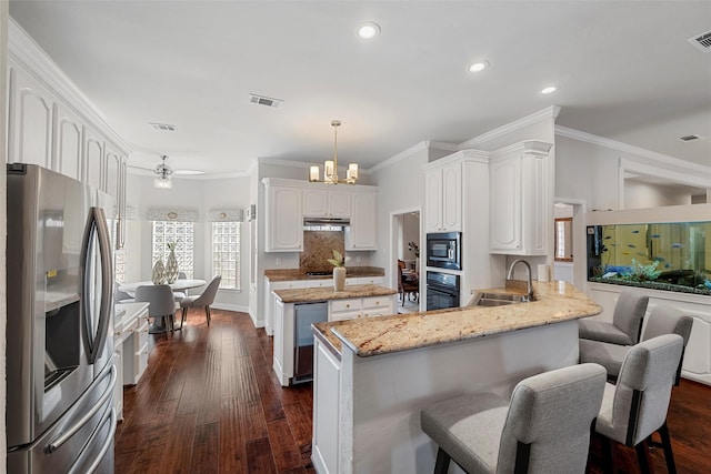 kitchen featuring stainless steel appliances, a peninsula, a sink, visible vents, and dark wood-style floors