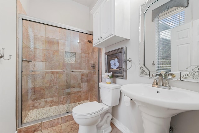 bathroom featuring a sink, baseboards, toilet, and a shower stall