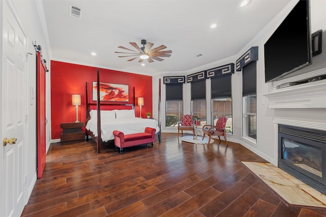 bedroom featuring wood finished floors, visible vents, recessed lighting, ornamental molding, and a barn door