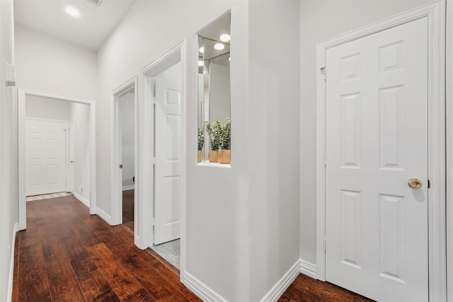 hallway featuring baseboards and dark wood-type flooring