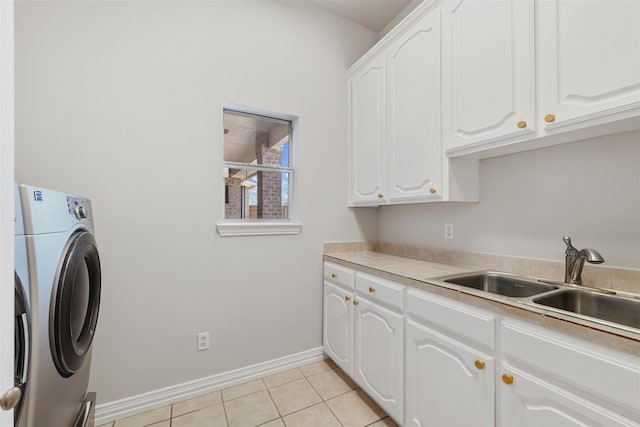 clothes washing area with light tile patterned floors, a sink, baseboards, cabinet space, and washer / dryer