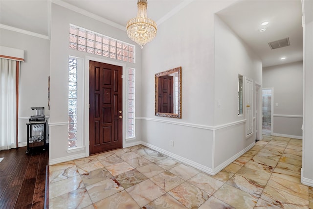 foyer entrance with visible vents, baseboards, and crown molding