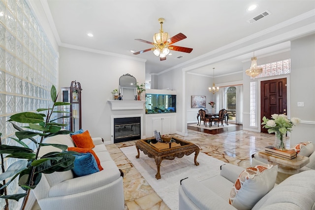 living room with visible vents, ornamental molding, ceiling fan with notable chandelier, a glass covered fireplace, and recessed lighting