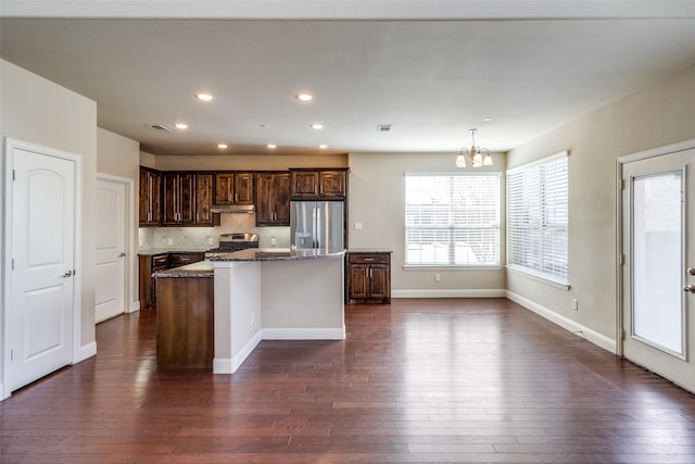 kitchen with dark stone countertops, a notable chandelier, appliances with stainless steel finishes, and dark wood finished floors