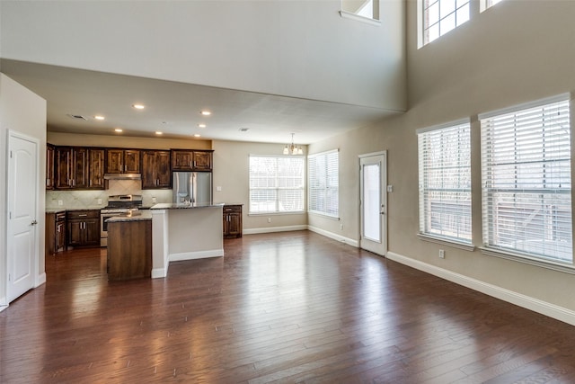 unfurnished living room with baseboards, a chandelier, dark wood-type flooring, and recessed lighting