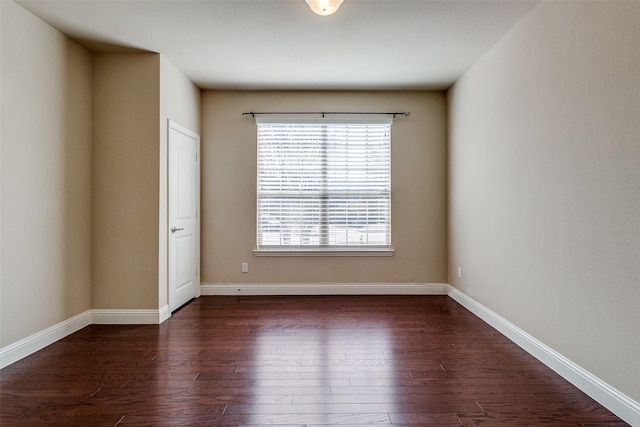 unfurnished room with baseboards and dark wood-style flooring