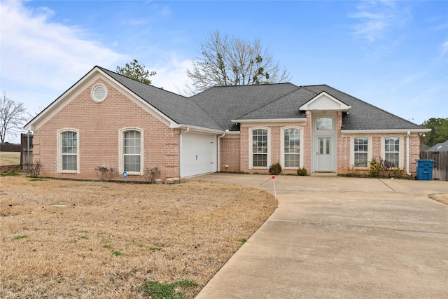 ranch-style house featuring brick siding, fence, concrete driveway, roof with shingles, and a garage