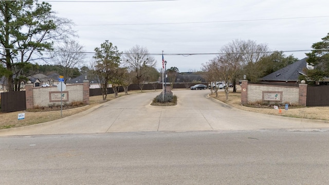 view of road with traffic signs, a gate, and curbs