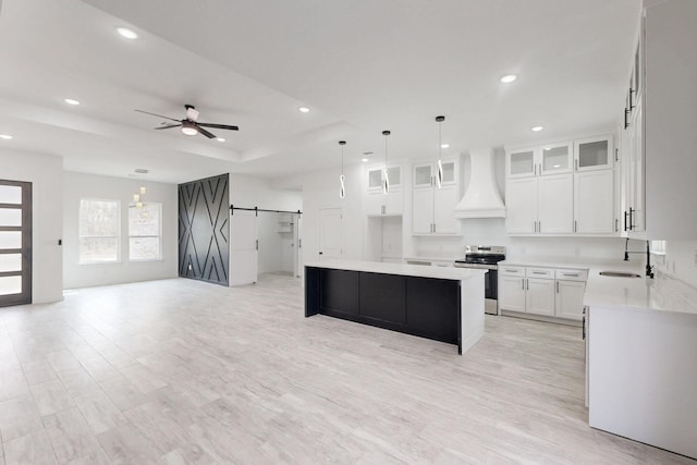 kitchen featuring stainless steel electric range oven, custom exhaust hood, a barn door, a kitchen island, and a sink