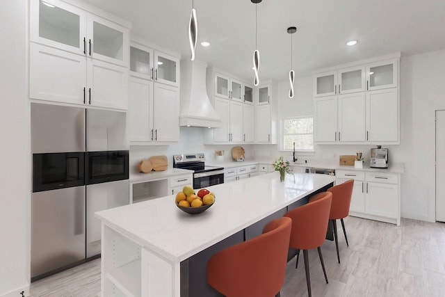 kitchen featuring a kitchen island, white cabinets, light countertops, appliances with stainless steel finishes, and custom exhaust hood