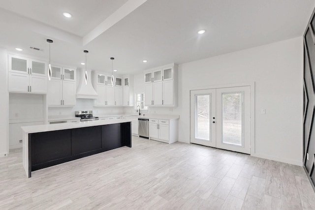 kitchen with stainless steel appliances, light countertops, visible vents, white cabinetry, and a kitchen island