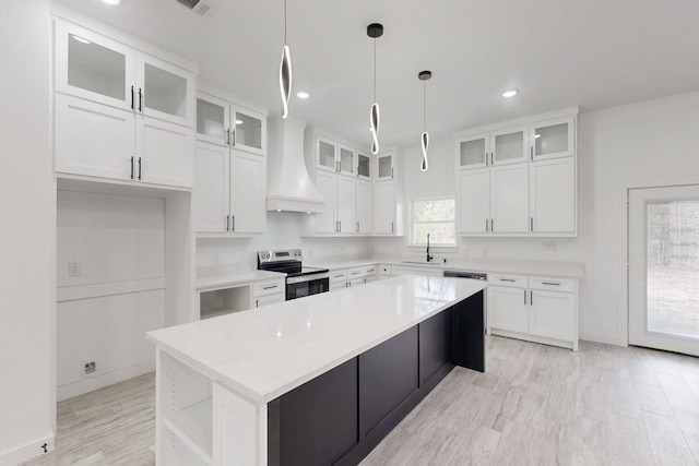 kitchen with custom exhaust hood, white cabinets, a kitchen island, stainless steel range with electric cooktop, and a sink