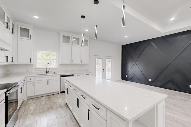 kitchen with a center island, appliances with stainless steel finishes, light wood-style floors, white cabinetry, and a sink