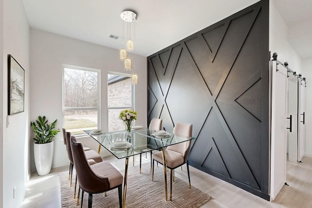 dining space featuring a barn door and visible vents