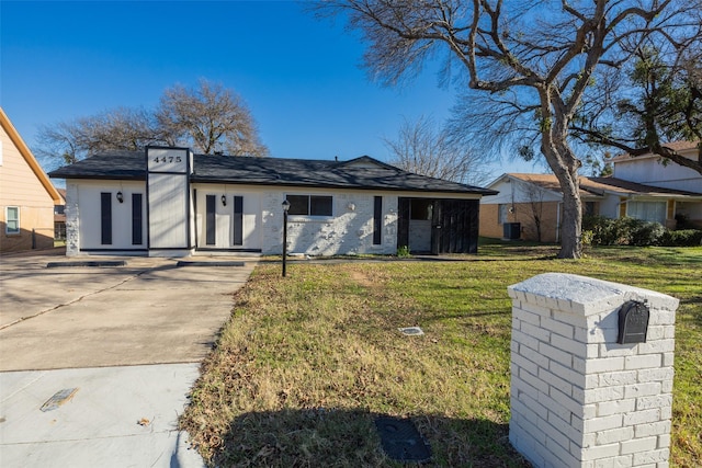 view of front of property with a front lawn, central AC unit, and brick siding