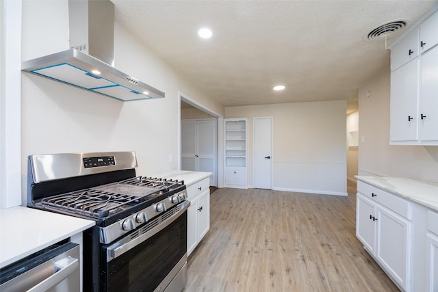 kitchen featuring visible vents, wall chimney range hood, appliances with stainless steel finishes, light wood-style floors, and white cabinetry