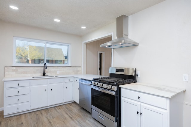 kitchen featuring a sink, stainless steel appliances, light countertops, wall chimney range hood, and backsplash