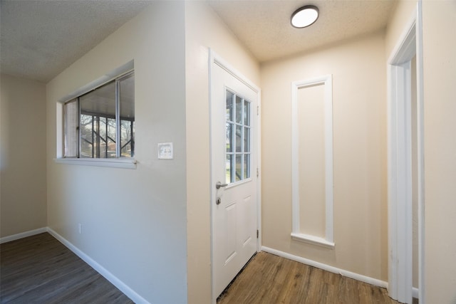 doorway to outside with wood finished floors, baseboards, and a textured ceiling
