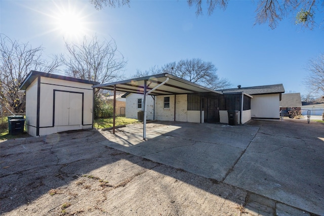 view of front of house featuring an outbuilding, driveway, a storage shed, and fence