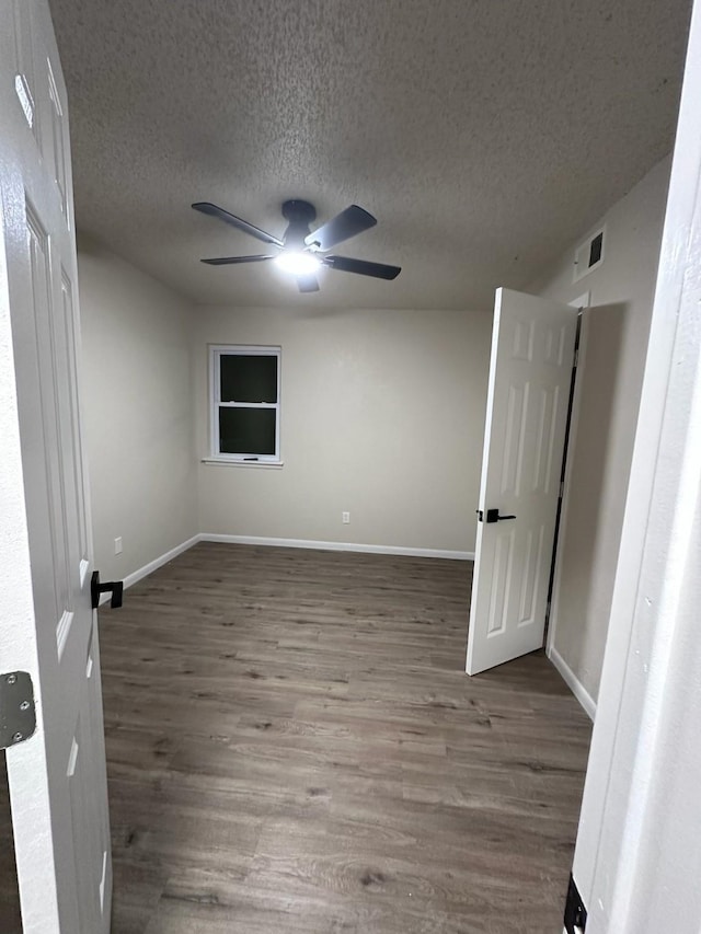 unfurnished bedroom with ceiling fan, a textured ceiling, baseboards, and wood finished floors