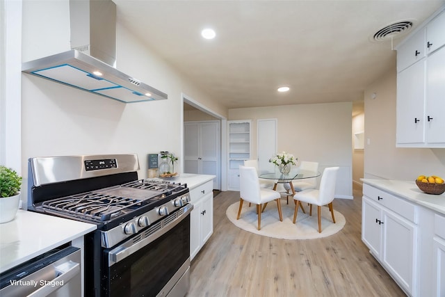 kitchen with visible vents, white cabinets, light wood-style floors, appliances with stainless steel finishes, and wall chimney exhaust hood