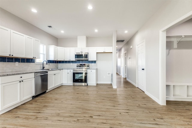 kitchen featuring appliances with stainless steel finishes, white cabinets, a sink, and backsplash