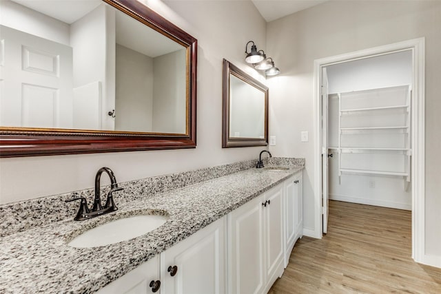 full bathroom with double vanity, baseboards, a sink, and wood finished floors