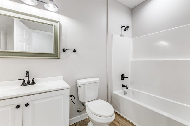 bathroom featuring baseboards, bathing tub / shower combination, toilet, wood finished floors, and vanity