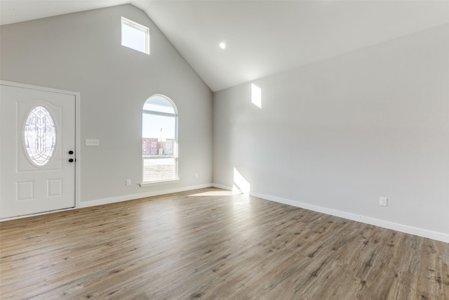 foyer entrance with high vaulted ceiling, light wood-style flooring, and baseboards