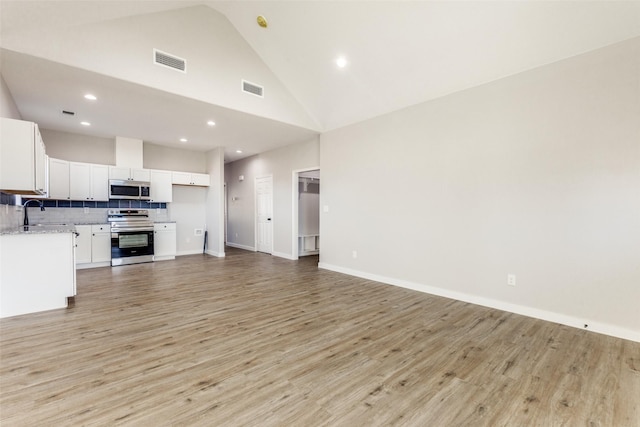 unfurnished living room featuring light wood finished floors, recessed lighting, visible vents, high vaulted ceiling, and baseboards