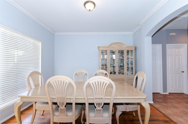 dining area featuring arched walkways, baseboards, and crown molding