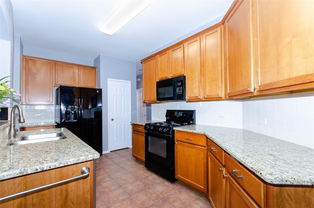 kitchen featuring light stone counters, light tile patterned floors, decorative backsplash, a sink, and black appliances