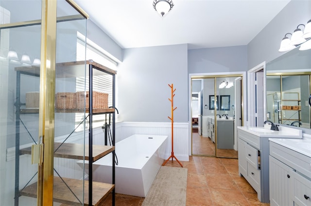 bathroom featuring a freestanding tub, a wainscoted wall, two vanities, a sink, and a shower stall