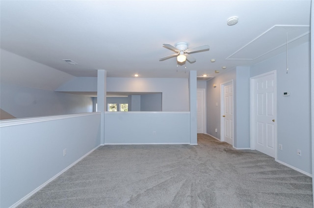 carpeted spare room with visible vents, baseboards, attic access, and a ceiling fan