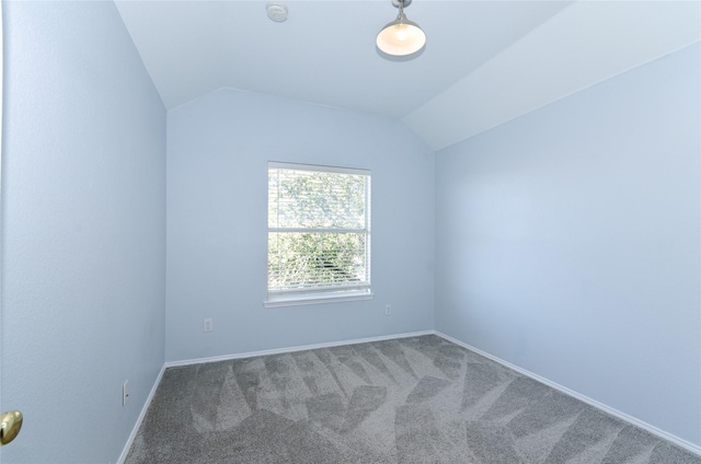 carpeted empty room featuring lofted ceiling and baseboards