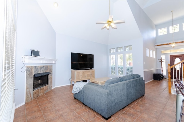 tiled living area with a healthy amount of sunlight, a fireplace, a towering ceiling, and baseboards