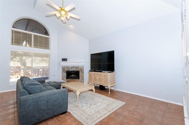 living area with high vaulted ceiling, tile patterned flooring, a ceiling fan, a high end fireplace, and baseboards