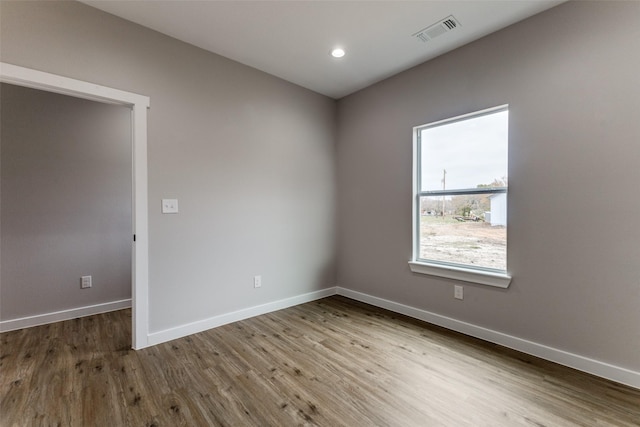 empty room with recessed lighting, visible vents, baseboards, and wood finished floors