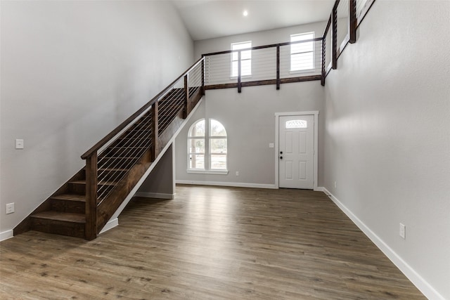 foyer entrance featuring baseboards, a towering ceiling, wood finished floors, stairs, and recessed lighting