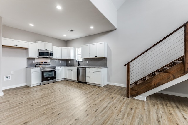 kitchen with stainless steel appliances, visible vents, decorative backsplash, and white cabinetry